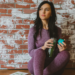 Woman enjoying matcha in a glass tumbler before a workout.